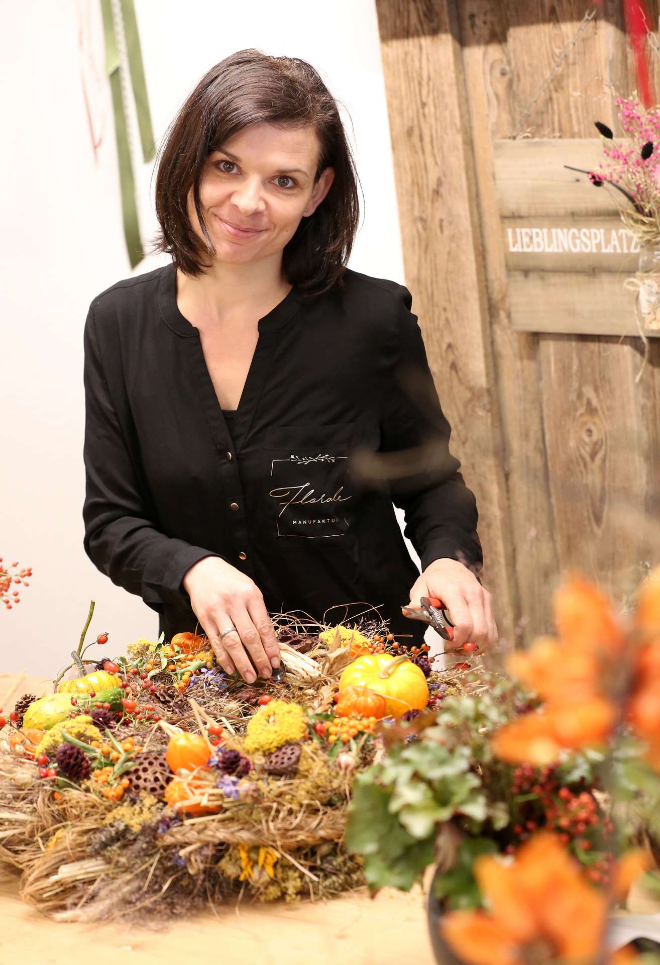 Floristin der Floralen Manufaktur arbeitet an einem herbstlichen Kranz
