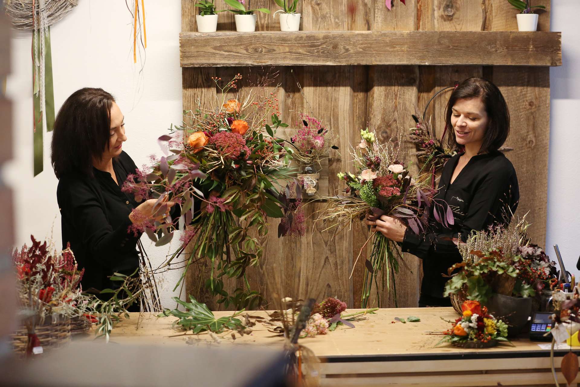 Zwei Floristinnen binden im Geschäft herbstliche Sträuße
